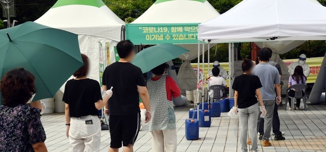 지난 21일 오전 연제구 부산시청 등대광장 임시선별검사소를 찾은 시민들이 진단검사를 받기 위해 줄을 선채 차례를 기다리고 있다.