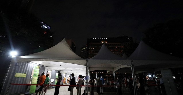 코로나19 확진자가 늘고 있는 22일 오후 서울 중구 서울광장에 마련된 임시 선별진료소에서 늦은밤 코로나19 검사자들이 줄지어 서 있다.