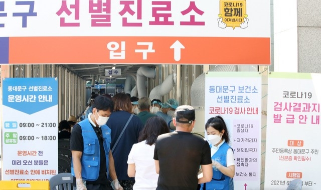코로나19 신규 확진자가 1842명으로 역대 최다를 기록한 지난 22일 오전 서울 동대문구 보건소에 마련된 선별진료소에서 시민들이 검사를 받기 위해 줄 지어 서 있다.