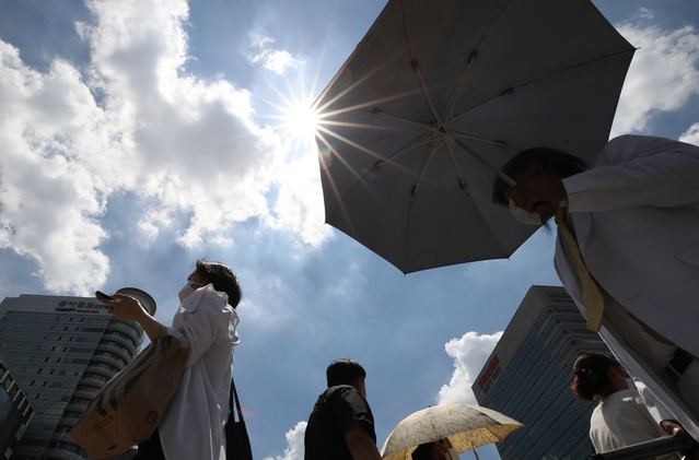 중복인 지난 21일 오후 서울 종로구 세종로 네거리에서 시민들이 뜨거운 햇살 아래 발걸음을 재촉하고 있다. 