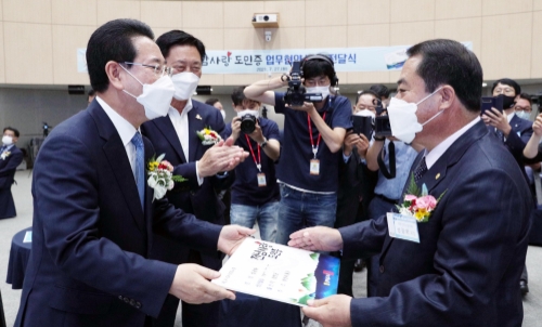 김영록 전라남도지사와 김한종 도의회 의장이 27일 오후 도청 왕인실에서 열린 전남사랑도민증 발급 업무협약 및 도민증 전달식에서 성광화 재부산향우회장에게 전남사랑 도민증을 전달하고 있다/사진=전라남도