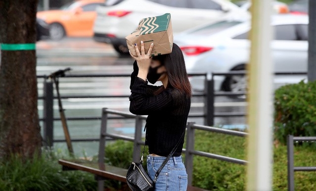 소나기가 내리는 지난 19일 오후 서울 강남구 삼성역 앞에서 한 시민이 종이가방으로 비를 피하고 있다.