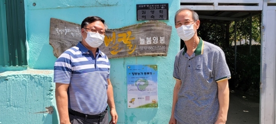 김환동 군청 축수산과장이 양봉등록 1호 농가 김영학씨에게 등록증 명패를 부착 후 기념 촬영을 하고 있다./사진=함평군