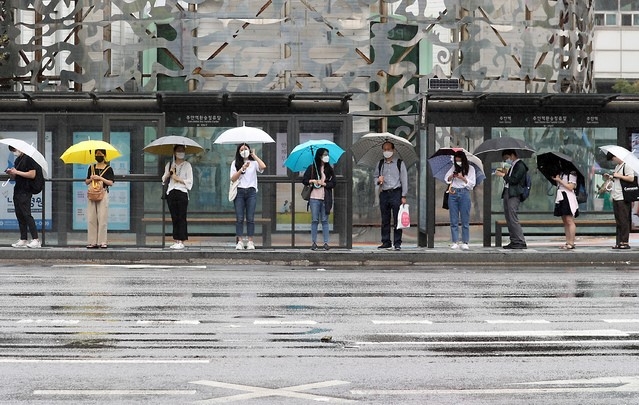 비가 오는 지난 7월 13일 오전 인천시 미추홀구 주안역 광장 버스정류장에서 시민들이 거리두기를 하면서 우산을 쓰고 버스를 기다리고 있다.