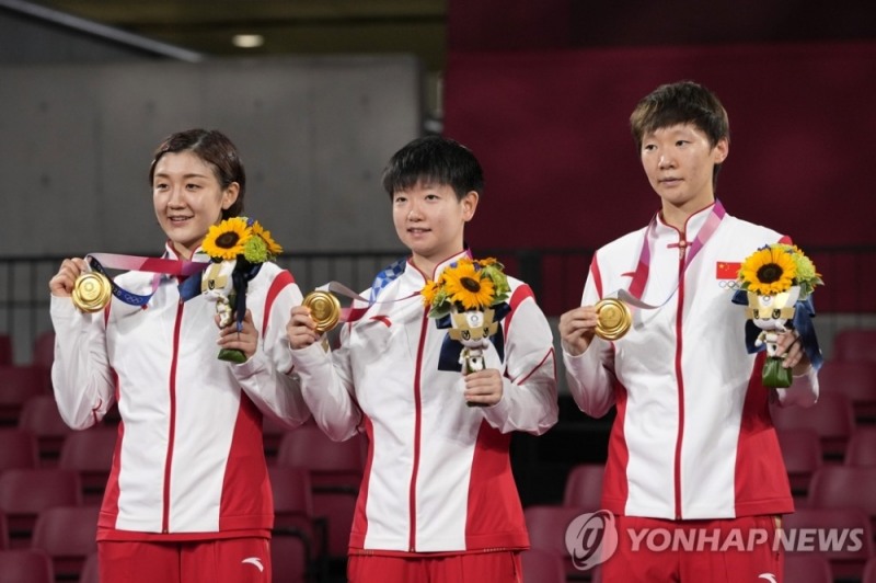 (도쿄 AP=연합뉴스) 중국의 천멍, 쑨잉사, 왕만위(왼쪽부터)가 5일 일본 도쿄체육관에서 열린 2020 도쿄올림픽 탁구 여자단체전 시상식에서 금메달을 목에 걸고 기뻐하고 있다. 중국 여자 탁구는 이날 일본을 3-0으로 완파하고 단체전이 도입된 2008년 베이징 대회부터 4개 대회 연속 단체전 금메달을 휩쓸었다. 특히, 앞선 3개 대회에서 모든 경기를 게임 점수 3-0으로 이긴 중국은, 이번 대회에서도 16강전부터 결승전까지 상대에 단 한 게임도 내주지 않고 승리하며 '퍼펙트' 4연패 행진을 이어갔다.
