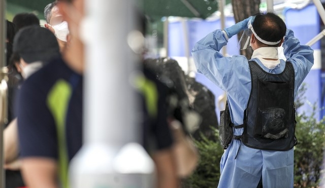 폭염 날씨가 이어지고 있는 지난 5일 오후 서울 동작구보건소에 설치된 코로나19 선별진료소에서 의료진이 얼음조끼를 입고 안내하고 있다.