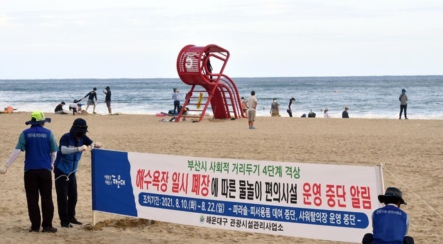부산시는 오는 10일 0시부터 22일 24시까지 사회적 거리두기를 4단계로 격상하고, 부산 7개 해수욕장을 모두 폐장하기로 결정했다. 폐장을 하루 앞둔 9일 오후 해운대해수욕장에서 구청 관계자들이 일시 폐장을 안내하는 현수막을 설치하고 있다.