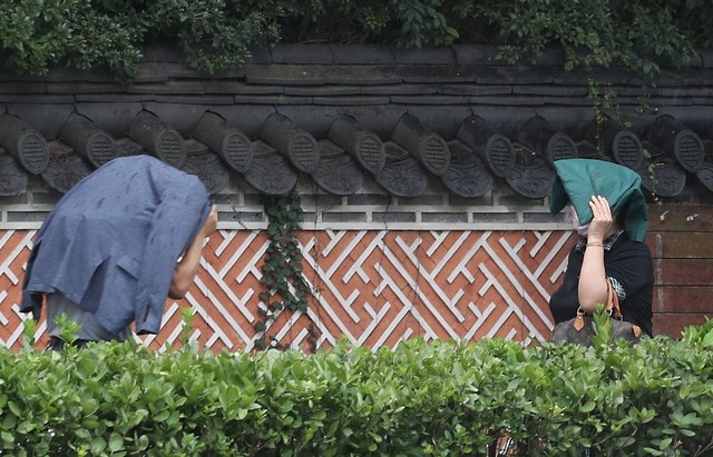 인천시 남동구 인천시청 앞에서 미처 우산을 준비하지 못한 시민이 양복 상의로 머리를 가리고 걸어가고 있다.