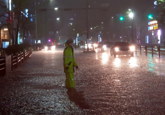 태풍경보가 발효된 24일 새벽 부산 부산진구의 한 도로에서 경찰관이 차량이 침수된 도로를 피해서 이동할 수 있도록 교통정리를 하고 있다. 2021.08.24. (사진=부산경찰청 제공).