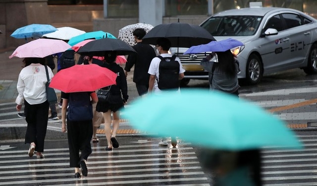 제12호 태풍 '오마이스'가 우리나라를 향해 북상하고 있는 23일 오후 서울 중구의 한 도로에서 시민들이 우산을 쓰고 지나가고 있다.