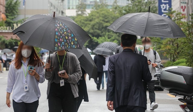 전국적으로 비가 내린 지난 27일 오후 서울 여의도공원 인근에서 시민들이 우산을 쓰고 이동하고 있다.
