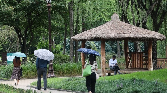 전국적으로 비가 내린 27일 오후 서울 여의도공원에서 시민들이 우산을 쓰고 이동하고 있다.