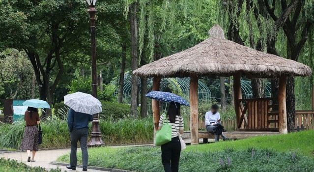 전국적으로 비가 내린 지난 27일 오후 서울 여의도공원에서 시민들이 우산을 쓰고 이동하고 있다.