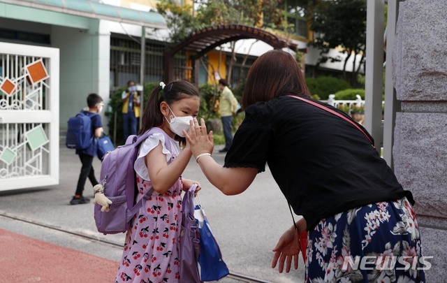 여름방학을 끝내고 전국 초·중·고등학교 상당수가 개학한 17일 오전 서울 강서구 월정초등학교 정문에서 한 학부모가 등교하는 딸과 인사를 하고 있다