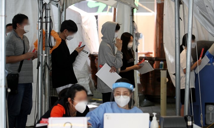 코로나19 신규 확진자가 2,050명으로 집계된 8일 오후 서울 노원구 보건소 선별진료소에서 시민들이 검사를 받기 위해 대기하고 있다.