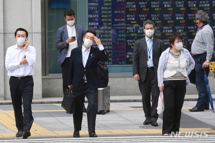 지난 6일 일본의 한 증권사 전광판 앞에서 마스크를 착용한 시민들이 길을 건너기 위해 기다리고 있다.