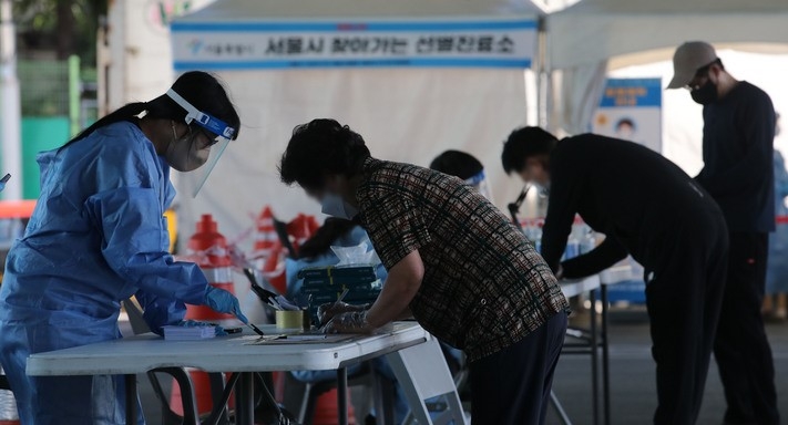 가락시장 관련 누적 확진자가 659명으로 집단감염이 지속되고 있는 26일 오전 서울 송파구 가락시장에 마련된 찾아가는 선별진료소에서 시장 종사자들이 검사를 받기 위해 문진표를 작성하고 있다.