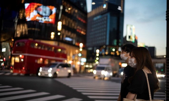 일본 수도 도쿄에서 23일 코로나19 예방을 위해 마스크를 착용한 시민들이 긴자 쇼핑가를 찾아 횡단보도를 건너려고 신호를 기다리고 있다.