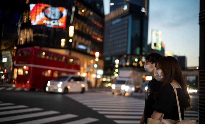일본 수도 도쿄에서 23일 코로나19 예방을 위해 마스크를 착용한 시민들이 긴자 쇼핑가를 찾아 횡단보도를 건너려고 신호를 기다리고 있다. 