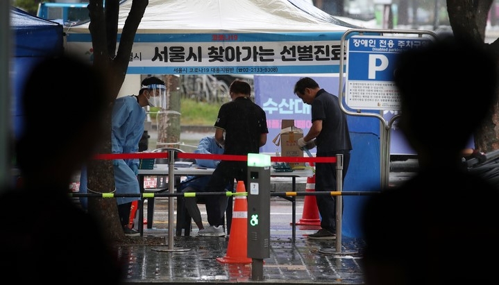 6일 오전 코로나19 확진자 집단감염이 발생한 서울 마포구 마포농수산물시장에서 시장 상인들이 찾아가는 선별진료소 모습을 지켜보고 있다.