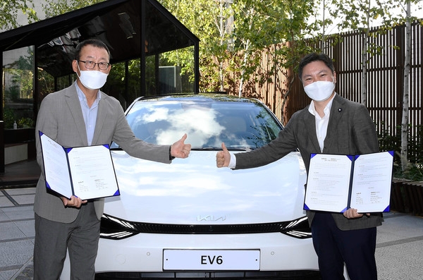기아 최신 전기차 EV6 앞에서 기아 이한응 전무와 휴맥스모빌리티 오영현 공동대표가 기념촬영을 하고 있다.