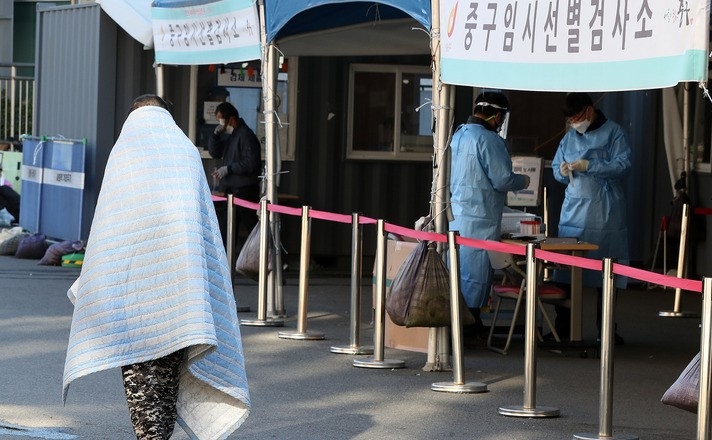 지난 17일 오전 서울 중구 서울역광장 임시선별검사소에서 한 시민이 담요를 덮고 있다.