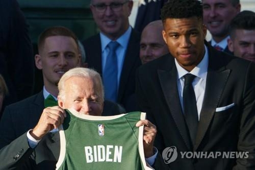 (워싱턴 AFP=연합뉴스) 조 바이든 미국 대통령이 8일(현지시간) 미국프로농구(NBA) 우승팀 밀워키 벅스로부터 선물받은 등번호 '46'의 유니폼을 들어올리며 웃고 있다. 오른쪽은 챔피언결정전 최우수선수(MVP) 야니스 아데토쿤보.