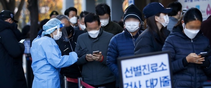 지난 12일 오전 서울 송파구보건소에 설치된 코로나19 선별진료소를 찾은 시민들이 검사를 받기 위해 줄 서 있다.
