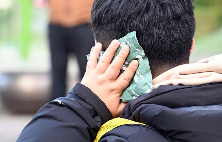 단계적 일상회복(위드 코로나)으로 수도권을 비롯한 전국의 유·초중고 학교에서 전면등교가 실시된 지난달 22일 오전 경기도 수원시 권선구 일월초등학교에서 한 학생이 핫팩을 들고 등교하고 있다.