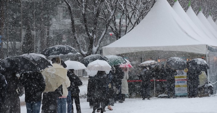 올 겨울 첫 대설주의보가 발령된 18일 오후 서울시청 코로나19 임시선별검사소에서 시민들이 검사를 받기 위해 눈을 맞으며 줄서 기다리고 있다