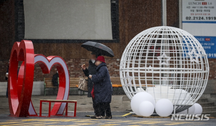 크리스마스를 하루 앞둔 지난 24일 오후 서울 중구 명동에서 눈을 맞으며 이동하고 있다.