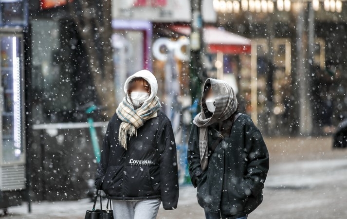 지난 17일 오후 서울 중구 명동거리를 찾은 시민들이 내리는 눈을 맞으며 이동하고 있다.