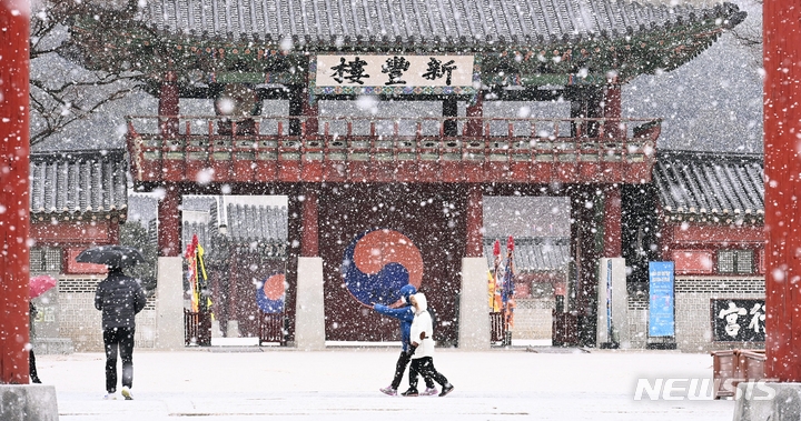 지난 19일 오후 경기도 수원시 팔달구 화성행궁에서 시민들이 함박눈을 맞으며 걸어가고 있다.