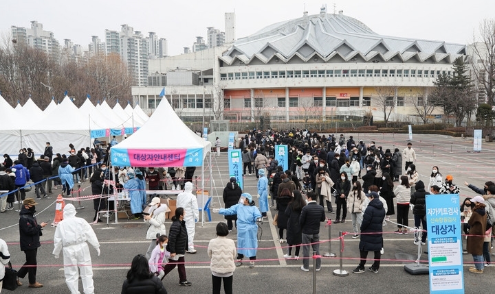 코로나19 신규 확진자가 5만6431명으로 역대 최다를 기록한 13일 오후 서울 송파구 잠실종합운동장 제2주차장 임시선별검사소에서 시민들이 검사를 받기위해 줄 서 있다.
