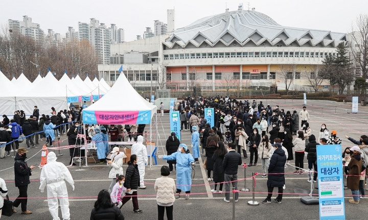 코로나19 신규 확진자가 5만6431명으로 역대 최다를 기록한 13일 오후 서울 송파구 잠실종합운동장 제2주차장 임시선별검사소에서 시민들이 검사를 받기위해 줄 서 있다.