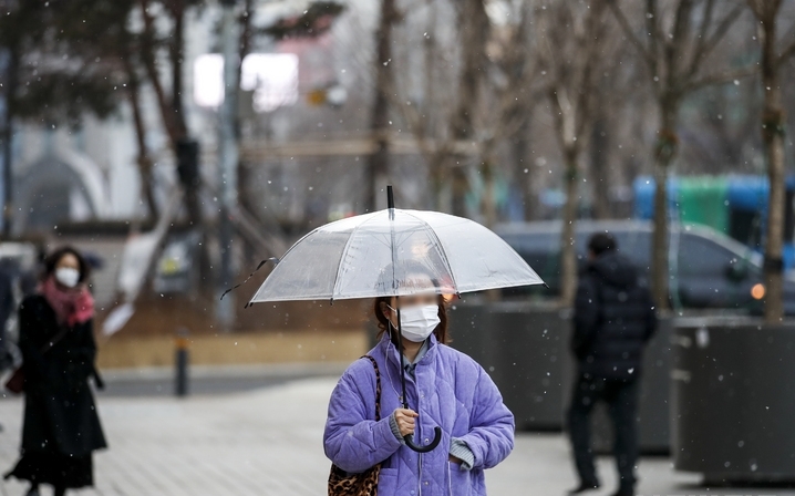 지난 15일 오전 서울 종로구 광화문네거리에서 두꺼운 옷차림을 한 시민들이 내리는 눈을 맞으며 이동하고 있다.