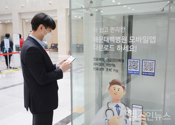 해운대백병원내원객이원내안내를보고모바일앱을설치하고있다.