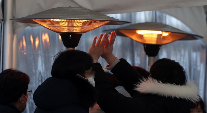 시민들이 온열기기에 몸을 녹이고 있다.