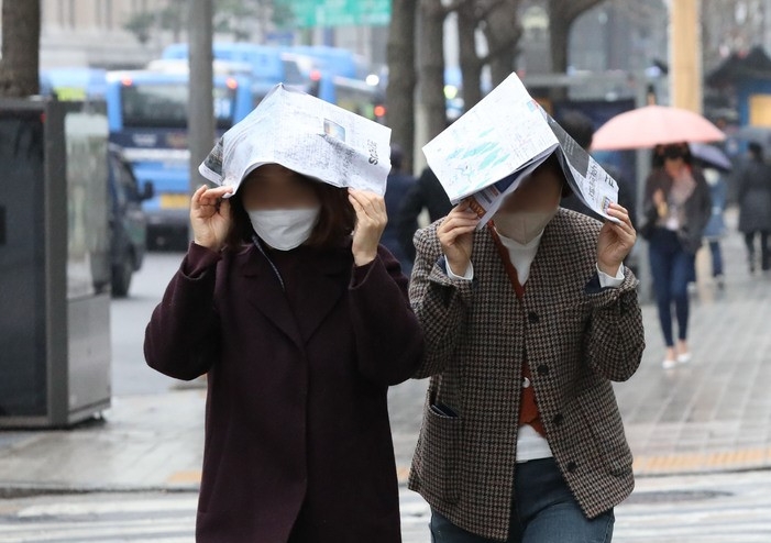 난달 14일 오후 서울 중구 을지로에서 미처 우산을 준비하지 못한 시민들이 신문을 머리에 쓰고 걸어가고 있다.