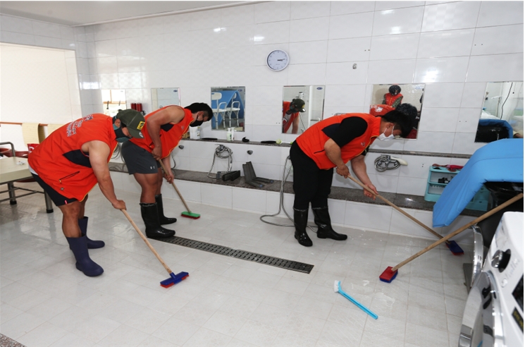 봉사활동에 참여한 경륜선수들이 구슬땀을 흘리며 목욕탕 청소를 하고 있다