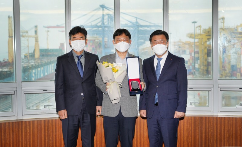 BNK경남은행 최홍영 은행장(오른쪽)이 부산신항만㈜ 박형준 차장(가운데)에 기업체 우수 사원 표창패와 꽃다발을 수여한 뒤 기념촬영하고 있다. <사진=BNK경남은행>