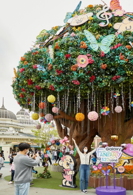 프로덕션522 멤버 박명수의 부캐인 사진작가 '명중만'이 추천한 사진 촬영 장소 매직트리에서 갤럭시 S22의 초고화질 카메라와 AI 지우개 기능을 체험하고 있다.