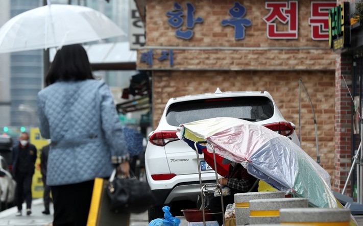 봄비가 내린 지난 3월 30일 오후 서울 도심에서 노점상이 파라솔을 쓰고 채소를 판매하고 있다.
