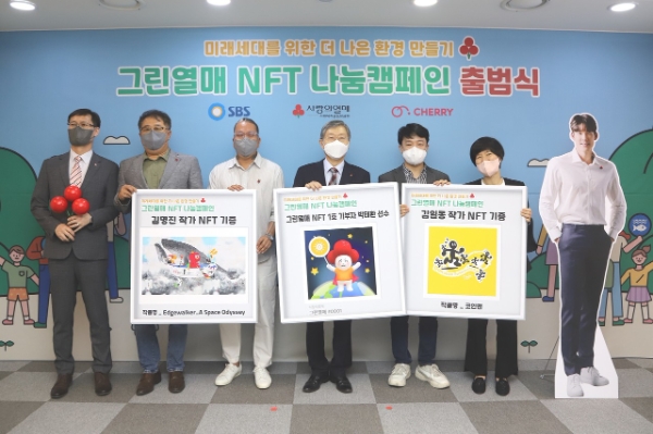지난 25일 사랑의열매와 SBS, 블록체인 기부플랫폼 체리가 서울 중구 사랑의열매 회관에서 ‘그린열매 NFT 캠페인’ 출범식을 진행하고 기념사진을 촬영했다. (왼쪽부터 사랑의열매 이정윤 전략모금본부 본부장, SBS 유영석 시사교양본부 부장, NFT 아티스트 김명진 작가, 사랑의열매 조흥식 회장, NFT 아티스트 김일동 작가, 블록체인 기부 플랫폼 체리 이수정 대표이사. 맨오른쪽 전신 사진은 박태환 선수)