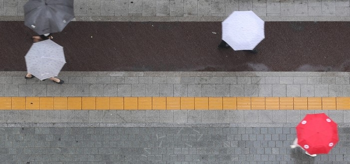 지난 27일 오후 서울 중구 세종대로에서 시민들이 우산을 쓰고 이동하고 있다.