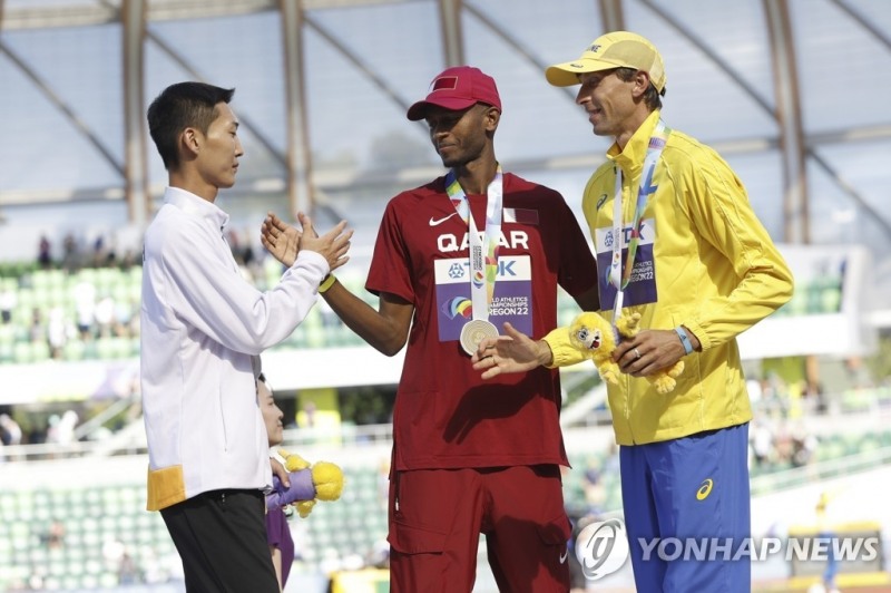 (유진 EPA=연합뉴스) 우상혁(왼쪽)이 20일(한국시간) 미국 오리건주 유진 헤이워드 필드에서 열린 2022 세게육상선수권대회 남자 높이뛰기 공식 시상식에서 1위 바심(가운데)에게 축하 인사를 하고 있다.