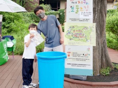 풀무원재단과 서울어린이대공원의 '보물줍깅' 캠페인에 참여한 가족이 대공원에 버려진 쓰레기를 수거한 후 쓰레기통에 버리고 있다.