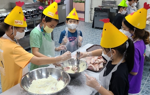 치킨대학 치킨캠프에 참여한 아이들이 황금올리브 치킨을 만들기위해 반죽을 묻히고 있다 / 사진 제공 = BBQ