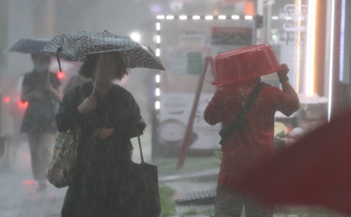 비가 내리고 있는 지난 8일 오후 서울 강동구 둔촌역 인근에서 한 시민이 대야를 쓰고 이동하고 있다. 