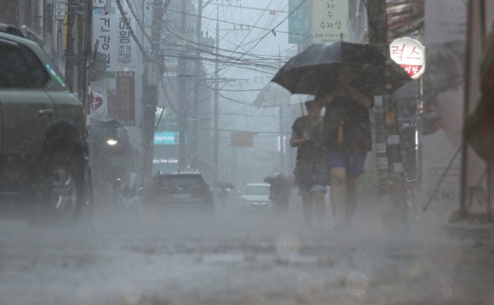 지난 8일 서울 강동구 둔촌역 전통시장에서 시민들이 우산을 쓰고 이동하고 있다.